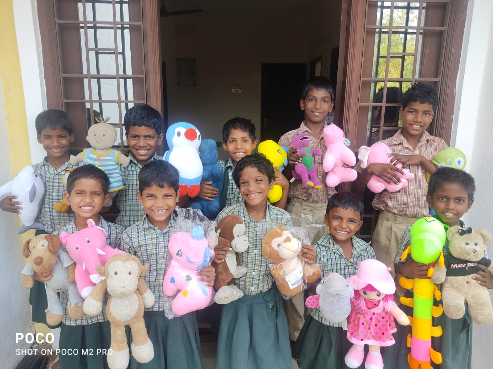 Children smiling together while holding soft toys at a CHES home