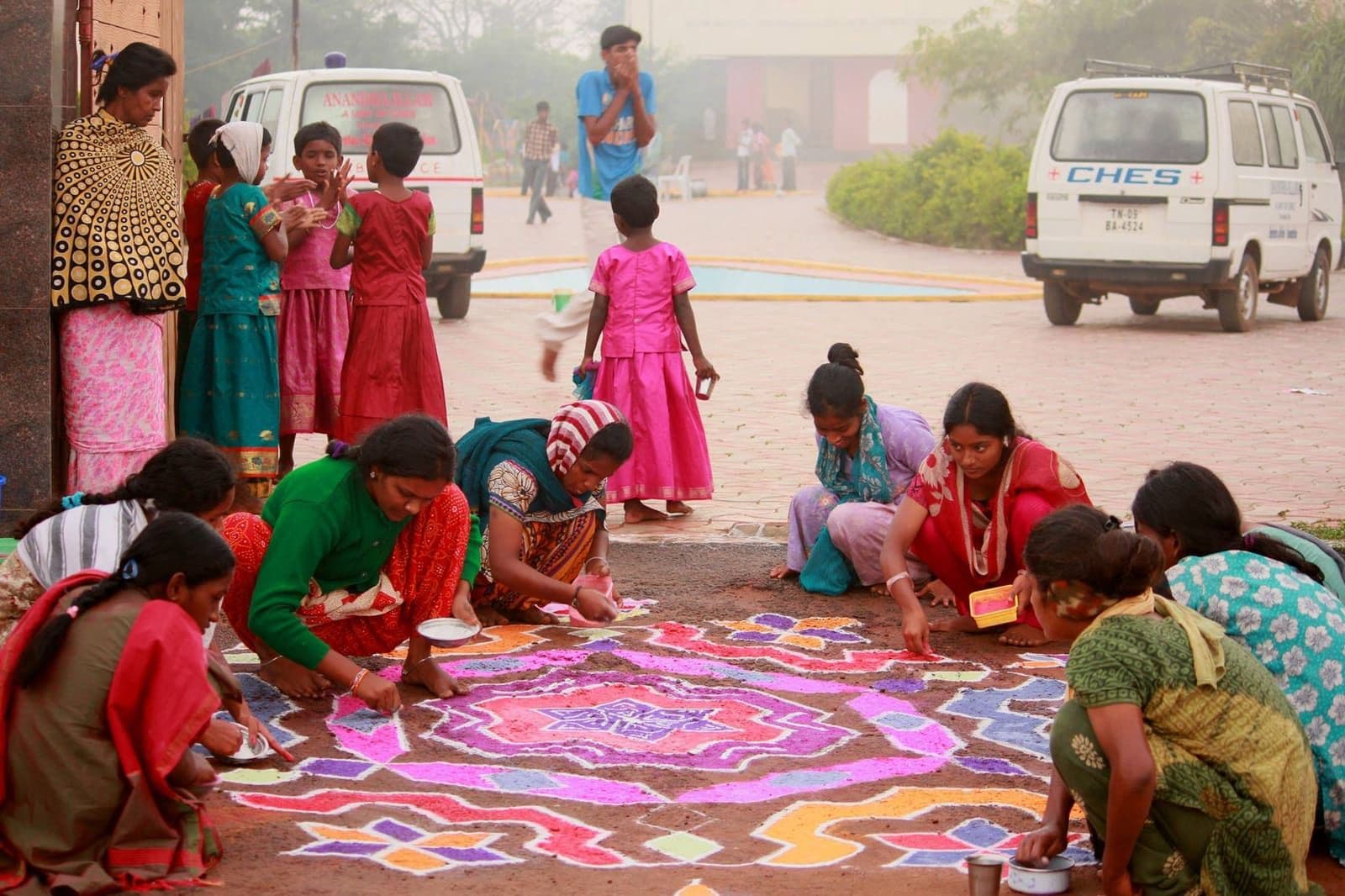 Children and community members creating a colourful kolam together